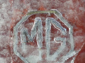 An MGA trunk badge is encased in ice