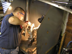 John massages the TR4A exhaust manifold for fit